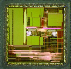 Die surface exposed by chemical decapsulation, with metallisation and circuit structures visible across the opened area.
